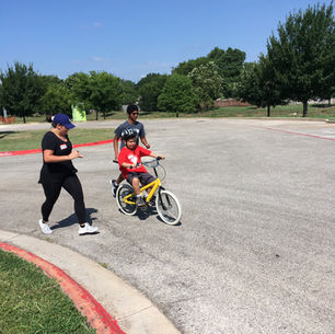 Volunteers running alongside a child riding a bike