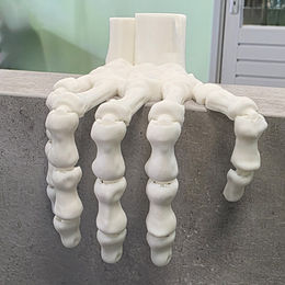 3D geprinte skelet hand met bewegende kootjes hangend over rand