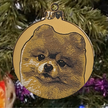 3D-geprinte kerstbal met portret van een Pomeriaan in goudtinten, hangend in een kerstboom