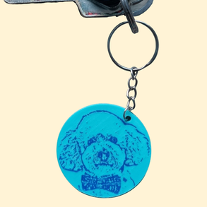 Ronde 3D-geprinte sleutelhanger in turquoise met blauw gegraveerd hondenportret en metalen sleutelring.