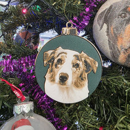 Kerstbal met 3D geprint portret van een hond op groene glitter achtergrond hangend in een kerstboom