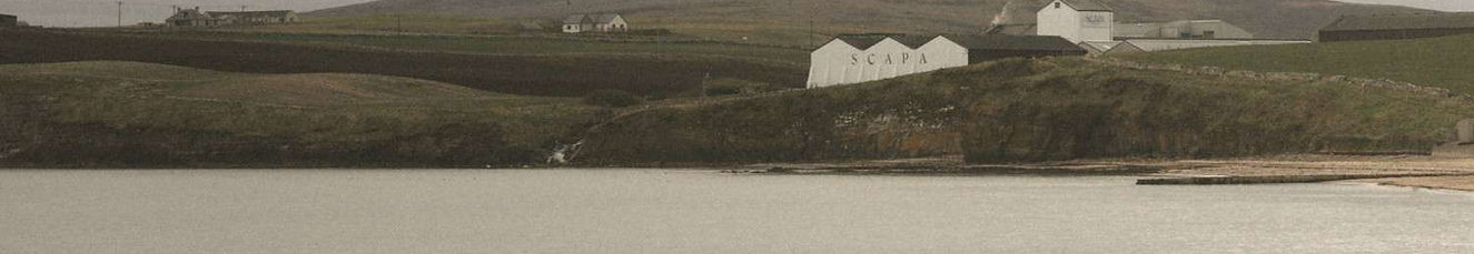The white sheds of Scapa Distillery as seen from the beach
