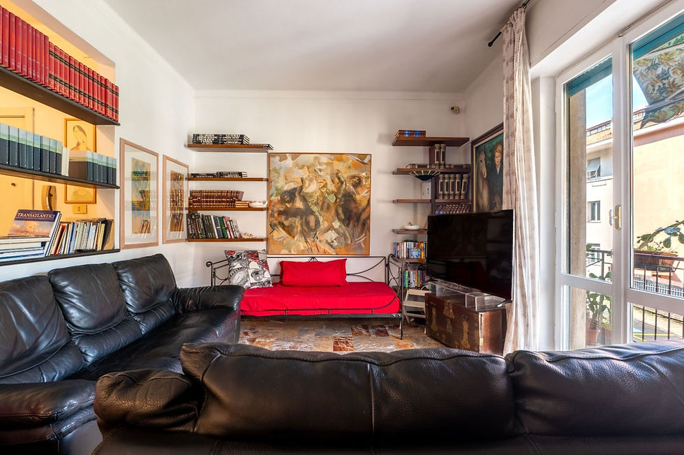 Salotto con libreria e divano in pelle in una casa vacanza a Chiavari, con affaccio sul balcone
