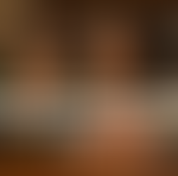 A beautiful African American woman sitting at her desk holding a pendulum, which she has hovering over the desk; behind her, a bookshelf of leather-bound books and crystal towers; the room is decorated in afrocentric bohemian; Lightworkers Garden