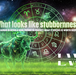 A Taurus symbol of a bull made of glowing green light, with sparkling and dazzling effects on the body, stands on a grassy, energy field against a dark cosmic background with a well-lit universe as the background; the zodiac wheel is behind the bull; Lightworkers Garden.