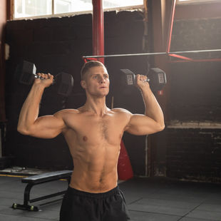 Fit man doing shoulder press with dumbbells