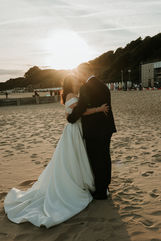golden hour on a beach and the bride and groom are embracing each other with a lens flare running through their silhouette