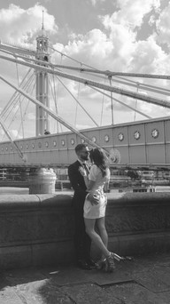 Albert Bridge in London is in the background of a bride and groom kissing