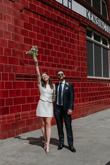 bride and groom smile outside of South Kensington Train Station