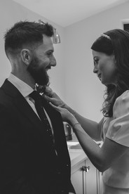 Bride helps her husband to be by putting on his button hole