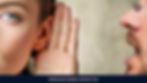Woman with one hand on her ear, listening attentively to what a person on her side is saying.