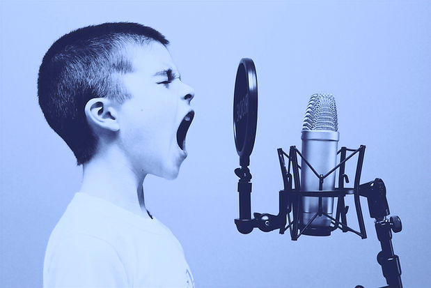 A boy on a microphone to demonstrate the opposite of dysphonia