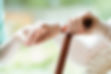 A therapist holding the hand of a patient with a cane
