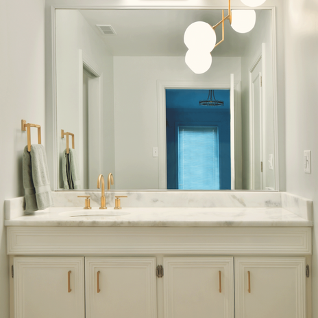 Hollywood regency bathroom remodel with white vanity, marble countertop, and brass chandelier.