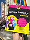 An image of the cover of the book "Neurodiversity For Dummies" held up in front of the iconic Castro Theatre in San Francisco.