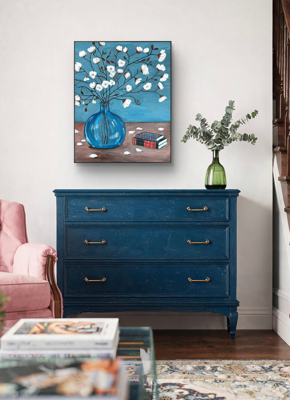 A still‑life painting featuring a round blue glass vase holding slender brown branches with soft white blossoms. A few white