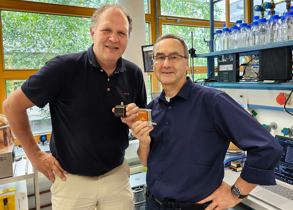 Rob ten Haaft von Bronkhorst und Frank Eiden von fermSYS stehen im Labor und halten jeweils stolz ein Produkt des jeweils anderen Unternehmens in der Hand.