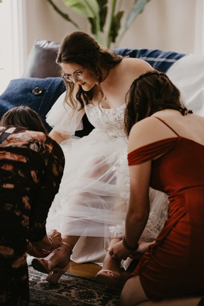 Family helping bride into shoes