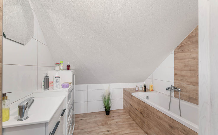 Koupelna v patře domu v Kunčině s vanou a úložnými prostory.