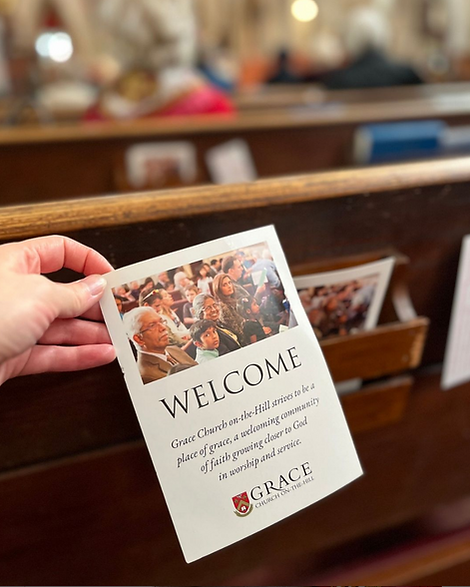 someone picking up a card that says 'welcome' from the church pew
