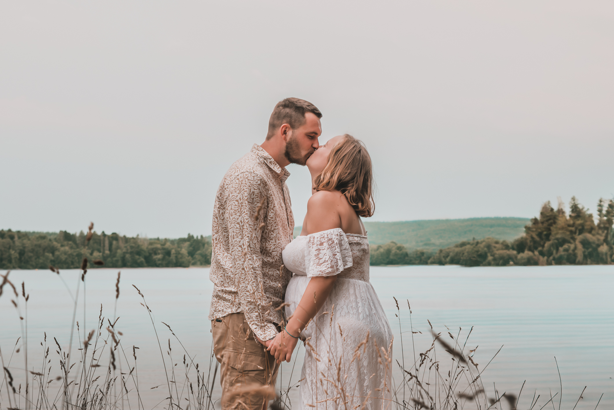 Séance photo grossesse dans l’Oise, couple de futurs parents s’embrassant devant un lac
