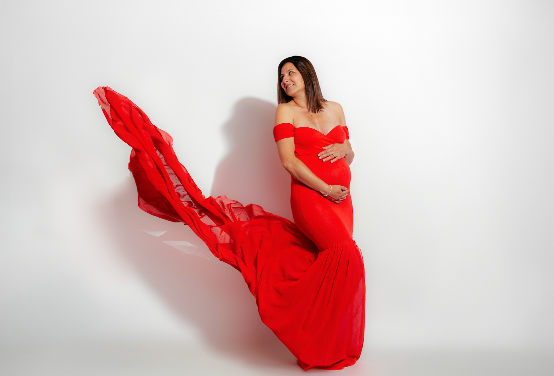 Séance photo grossesse en studio mobile dans l’Oise, jeune maman posant avec robe au voilage flottant