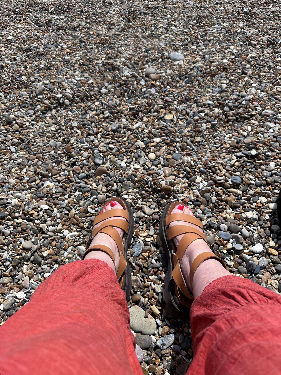 Feet in sandals on a pebbly beach