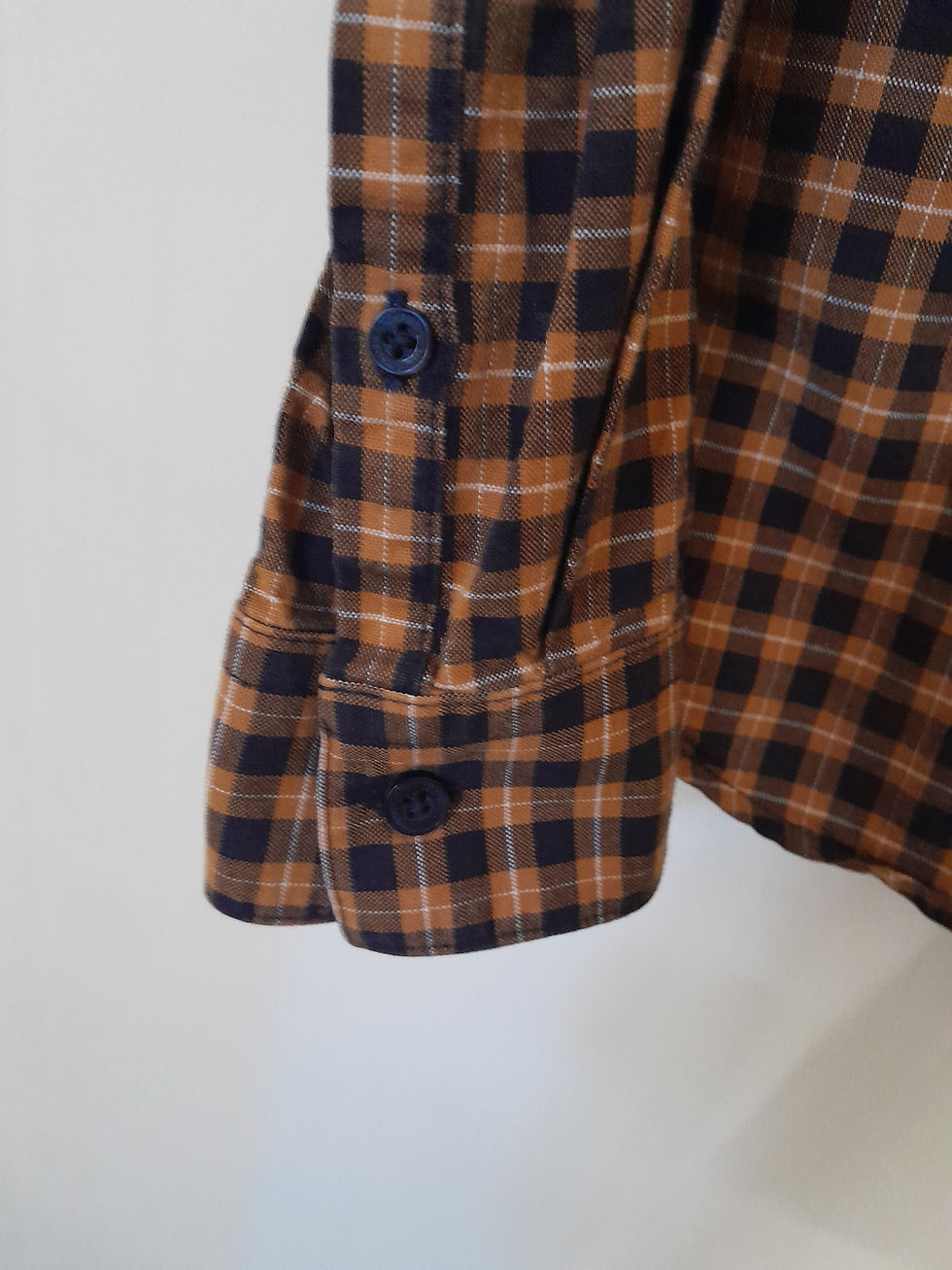 Miniature : Détail d'une chemise à carreaux marron et bleu marine, bouton fermée, seconde main.
