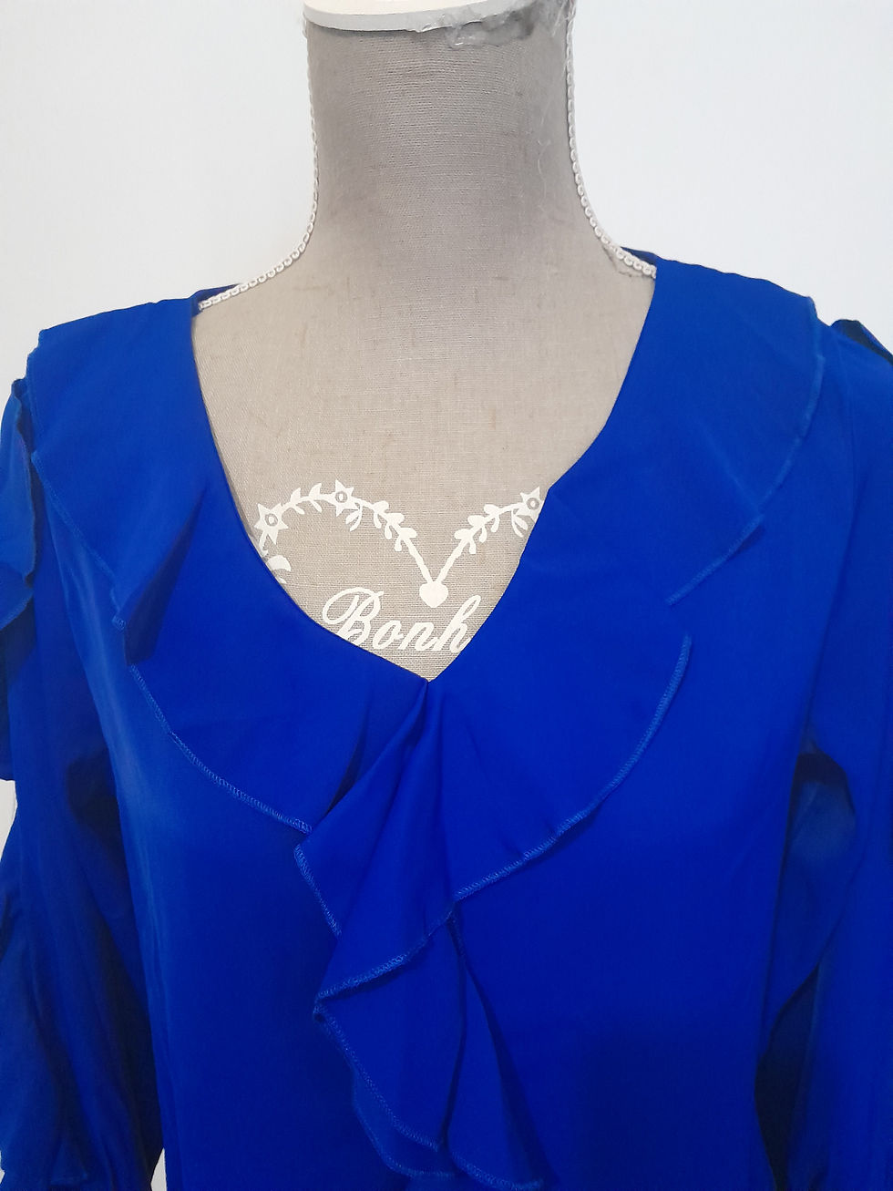 Miniature : Robe bleue sur mannequin avec encolure en V, cœur blanc, et volants.