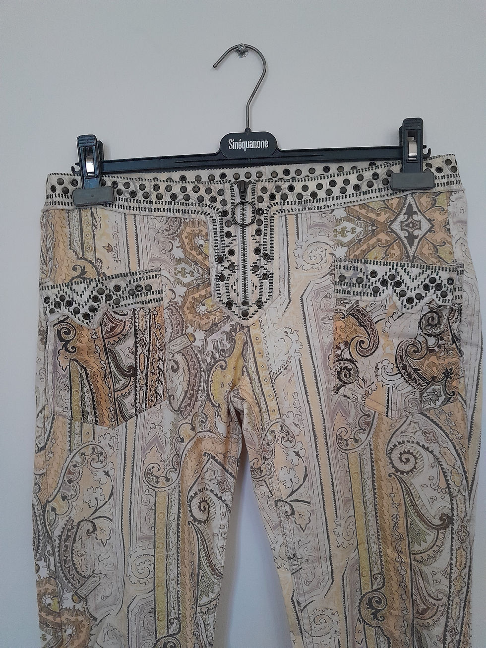 Miniature : Pantalon beige orné de motifs et détails, accroché sur un cintre, seconde main.