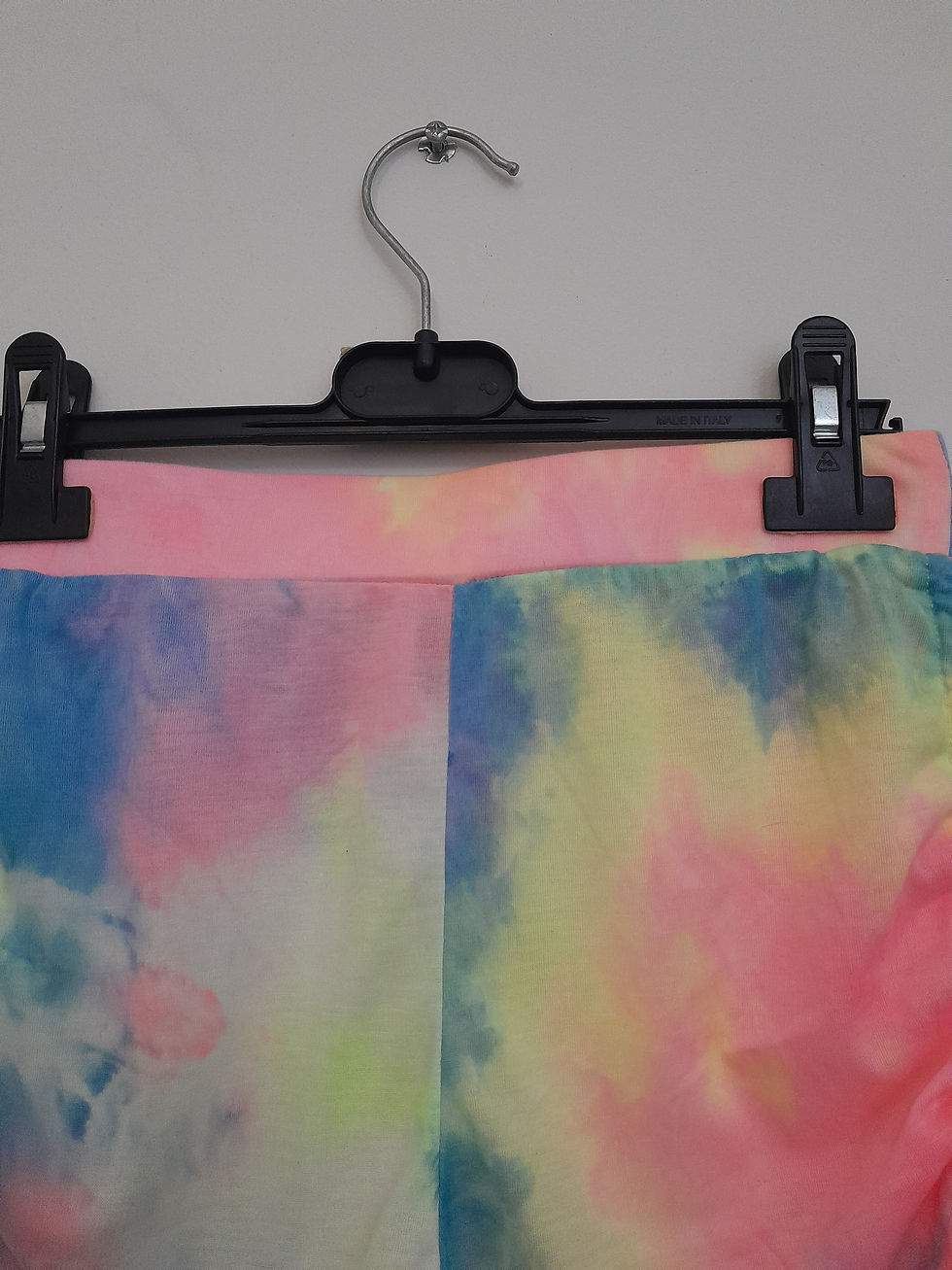 Miniature : Pantalon tie-dye coloré accroché sur un cintre, prêt pour être porté. Seconde main.