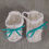 Miniature : Une paire de chaussures de bébé blanches avec des rubans bleus turquoise.
