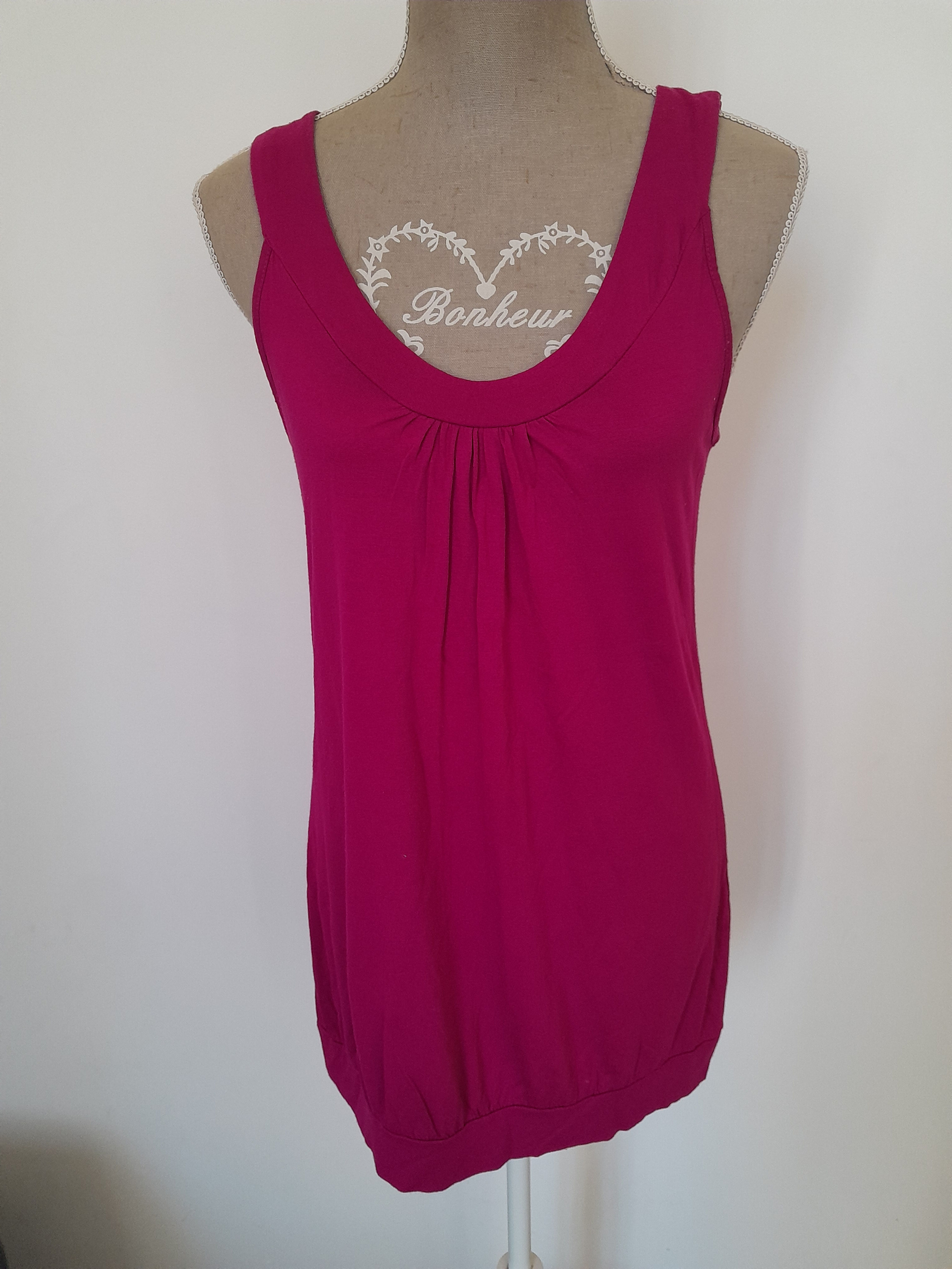 Un haut rose vif devant un fond blanc, coeur imprimé. Seconde main