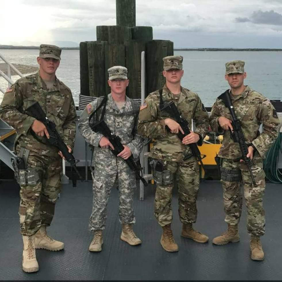4 solders stand holding rifles. Their faces are obscured by their uniform hats.
