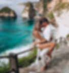 um casal em uma trilha rochosa à beira-mar, com imponentes falésias ao fundo. O homem está segurando a mulher, que está se inclinando para ele enquanto trocam um beijo íntimo. O cenário é deslumbrante, com águas turquesa e vegetação ao redor. Ambos estão vestidos de branco, o que realça a atmosfera romântica e tranquila do moum casal em uma trilha rochosa à beira-mar, com imponentes falésias ao fundo. O homem está segurando a mulher, que está se inclinando para ele enquanto trocam um beijo íntimo. O cenário é deslumbrante, com águas turquesa e vegetação ao redor. Ambos estão vestidos de branco, o que realça a atmosfera romântica e tranquila do momento.mento.