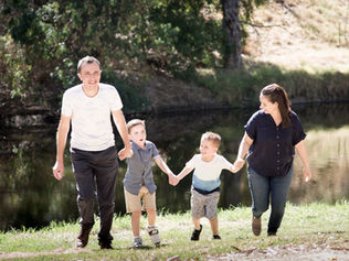 A happy family of four walking hand-in-hand by a lake | Margarita Ceko Photography