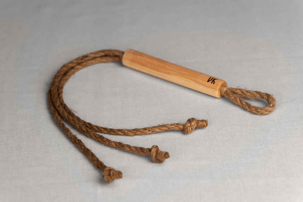 Flogger with three ropes laying on bed