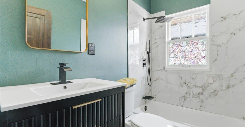 Renovated bathroom with marble-style tile, modern vanity, and rain shower head
