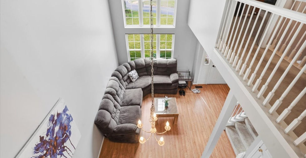Dramatic two-story foyer overlooking the living room with oversized windows and chandelier.
