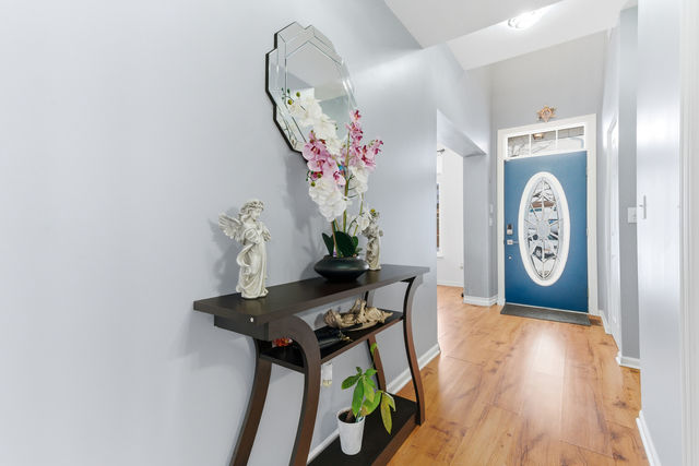 Entry foyer with blue front door, wood floors, console table, and decorative mirror
