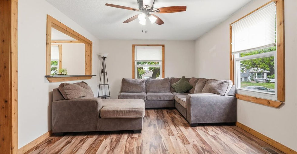 Bright living room with wood-look flooring, large windows, and a spacious sectional sofa