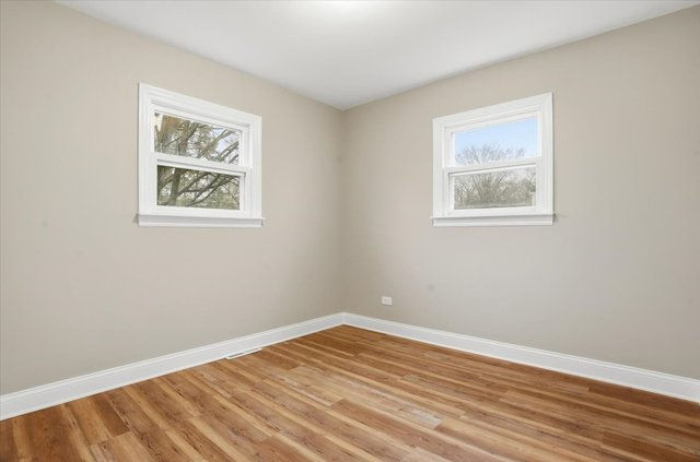 Clean, bright bedroom with neutral paint, natural light, and wood-look floors.