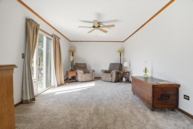 Spacious family room at 3413 Harbor Ridge Dr in Zion, IL with carpet, ceiling fan, and sliding glass door