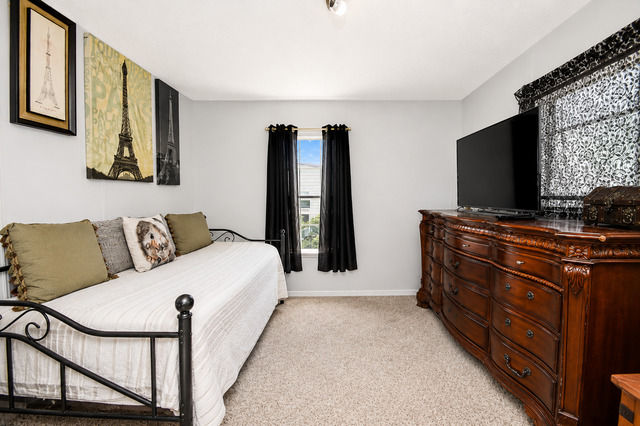 Guest bedroom with daybed, carpet flooring, dresser, TV, and window