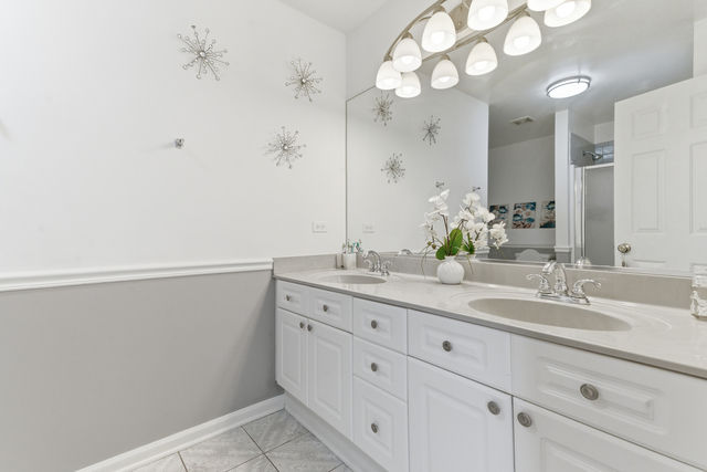 Primary bathroom with double sink vanity, large mirror, and bright lighting