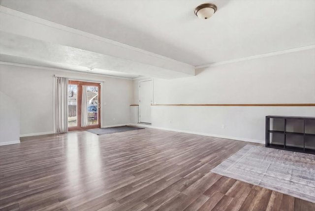 Lower-level family room with wood-look flooring, neutral walls, and exterior walkout door.