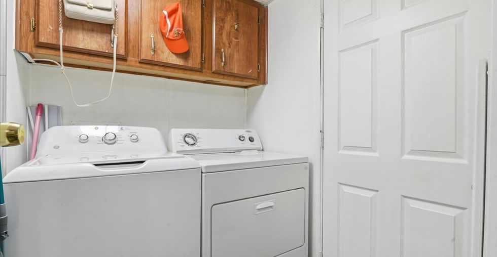 Laundry area with washer and dryer, overhead wood cabinets, and white double doors.