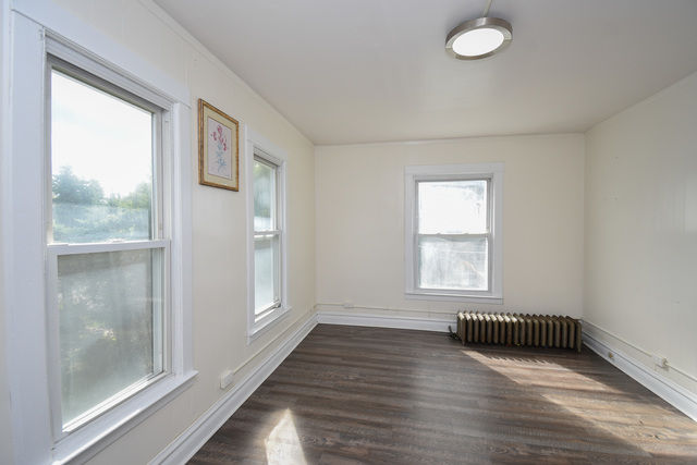 Bedroom with three windows and natural light, featuring baseboard heater