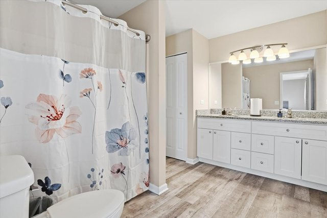 Bathroom with dual-sink vanity, large mirror, and shower/tub combo.