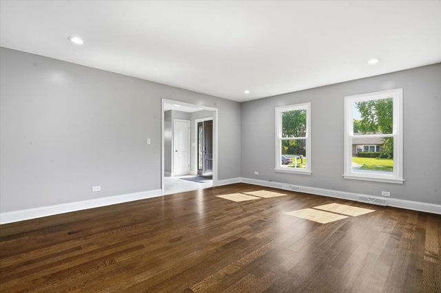 Bright living room with hardwood floors, recessed lighting, and large front-facing windows
